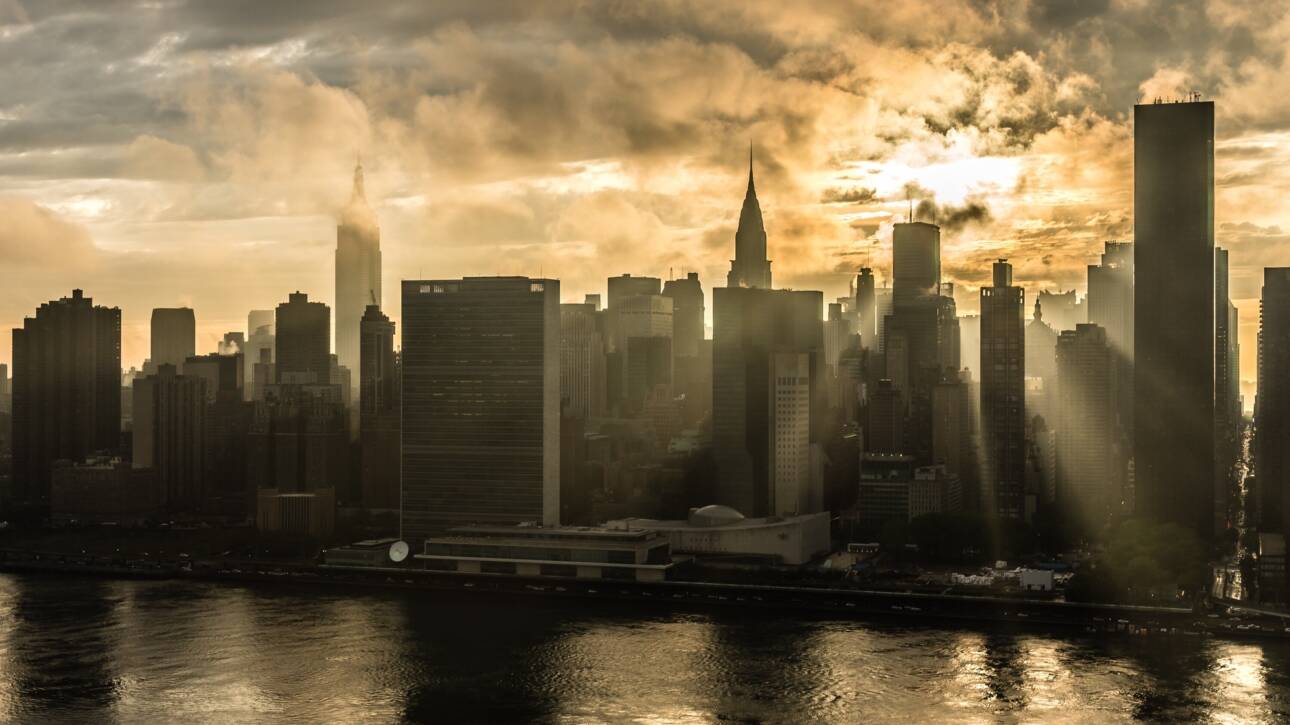 Crazy clouds and sun rays penetrating through Manhattan skyscrapers at sunset.